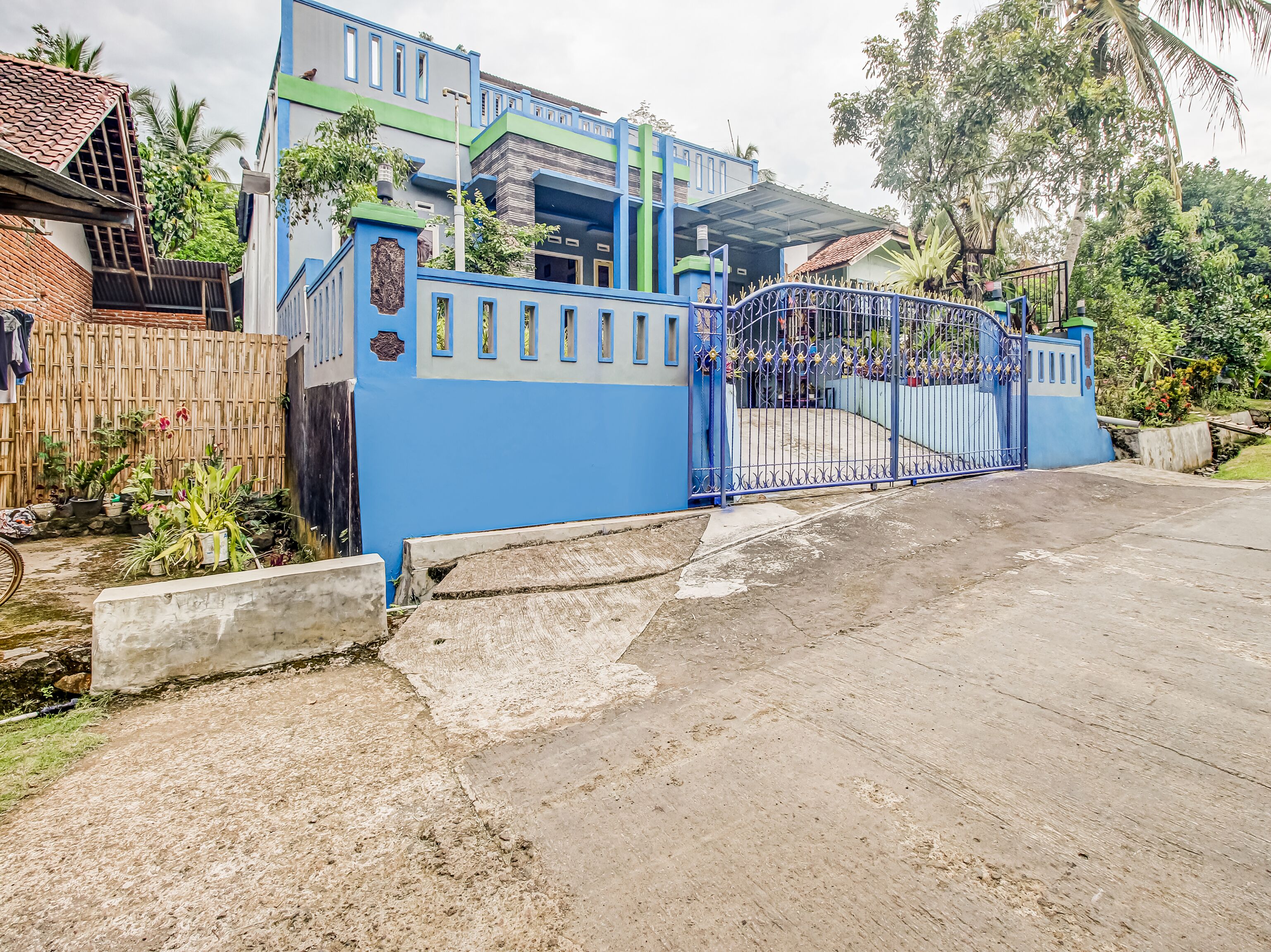 Zona residencial privada con una reja azul y una casa con techo de tejas.