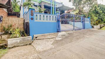 Zona residencial privada con una reja azul y una casa con techo de tejas.
