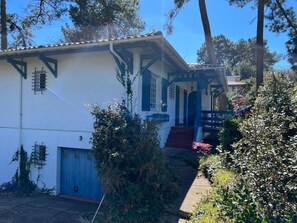 A white building with blue accents, a covered porch, and a red door. - Pyla-sur-Mer (La Teste-de-Buch)
