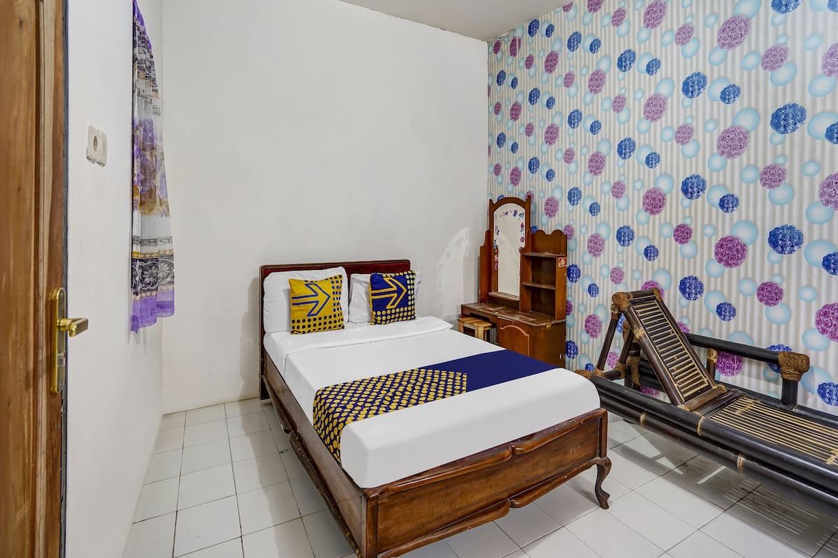 A bedroom with a wooden bed, two pillows, a nightstand, a mirror, and a chair.