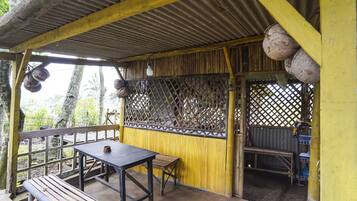 A covered outdoor seating area with a table and benches, surrounded by a wooden fence and a lattice screen.