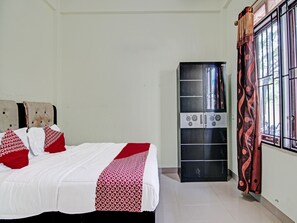 A bedroom with a bed, a wardrobe, and a window with curtains. - OYO 91642 Fhazel Residence Syariah (Pekanbaru)