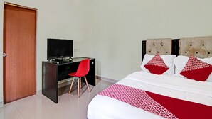 A hotel room with a bed, a desk with a TV, a red chair, and a door. - OYO 91642 Fhazel Residence Syariah (Pekanbaru)