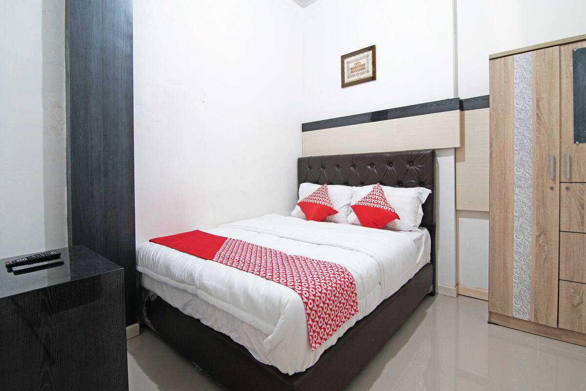 Een netjes ingerichte slaapkamer met een bed, nachtkastje, kledingkast en een lijst met een afbeelding aan de muur.