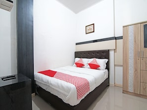 Un dormitorio ordenado con cama, mesita de noche, armario y un cuadro en la pared.