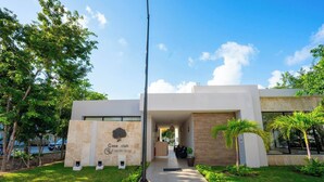 A modern building with a reception area, a sign reading 'Casa Club Grupo Veleas,' and a pathway leading to the entrance. - Luxury Apartment With Poll (Playa del Carmen)