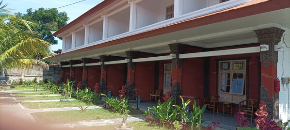 A building with a red facade, white columns, and a covered porch with chairs.