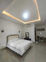 Un dormitorio con cama, mesita de noche, espejo y un equipo de aire acondicionado en la pared.