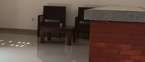 A spacious room with a polished floor, a wooden bench, a small table, and a brick accent wall.