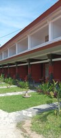 Un edificio con fachada roja y un espacio al aire libre cubierto con sillas y un pequeño jardín.