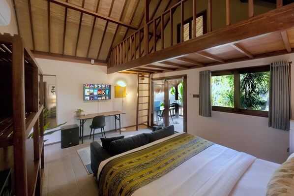 A bedroom with a large bed, a desk with a computer, a chair, and a view of greenery through a window. - The Social - Begadang Gili Air (Gili Air)