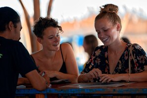 Tres personas sentadas en una mesa de madera, conversando.