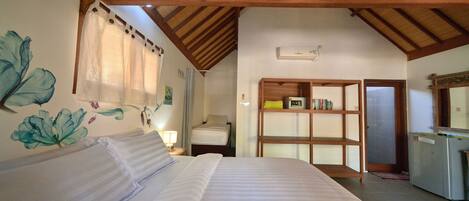 A bedroom with a bed, a wooden ceiling, a wall with a floral mural, a bedside table with a lamp, and a wardrobe.
