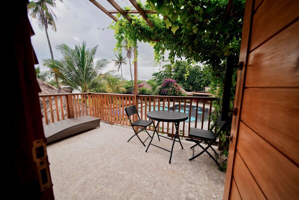 A patio with a table and chairs, a pool, and a wooden fence.
