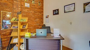 A reception desk with a laptop, a calendar, and certificates on the wall. - Hotel O Desa Wisata Alam Gosari (wagos) (Gresik)