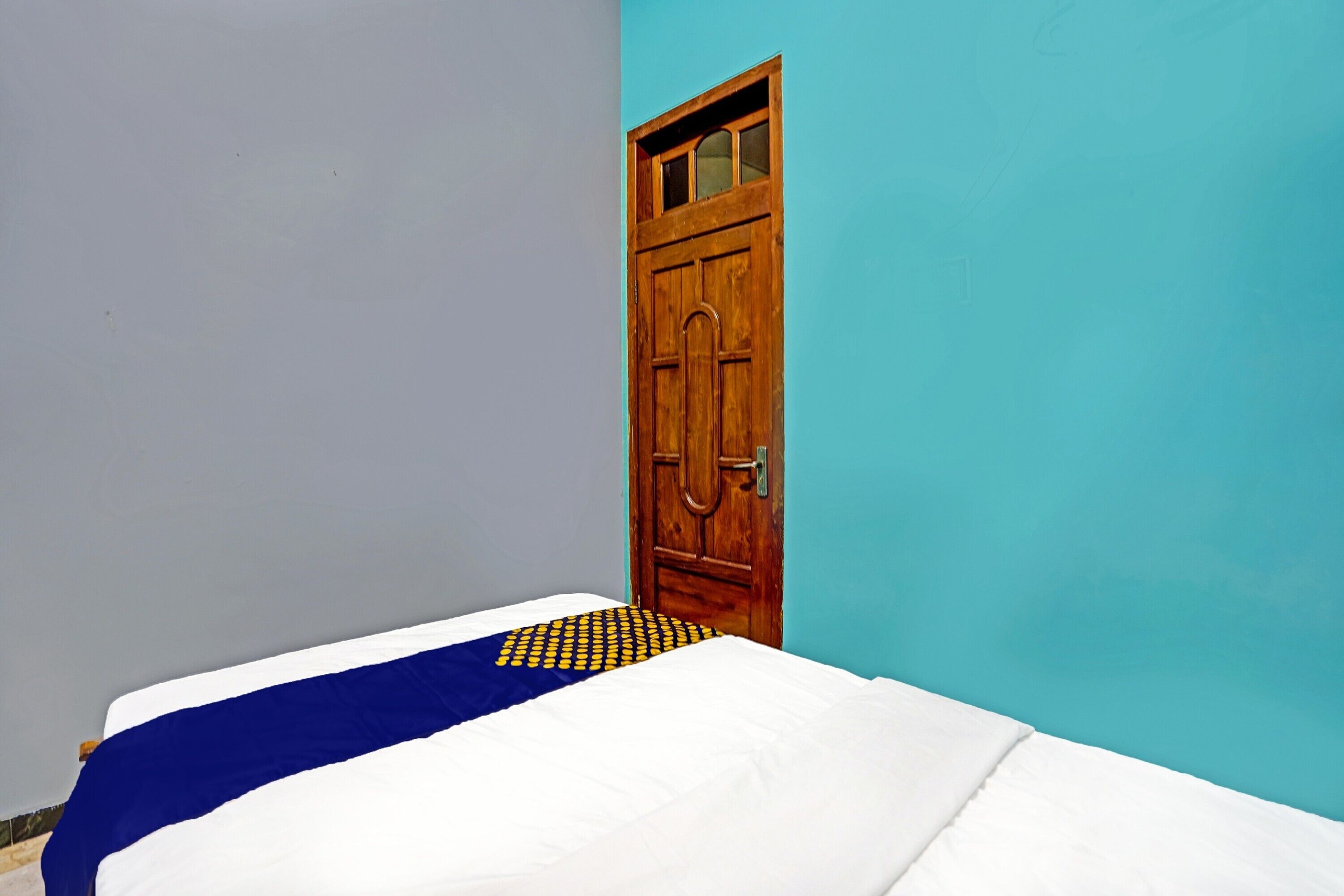 Une pièce avec un lit, une porte en bois et un mur bleu.
