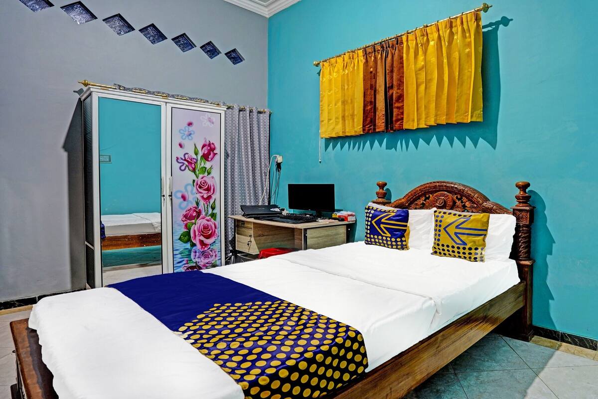A bedroom with a bed, a desk, a computer, and a wardrobe.