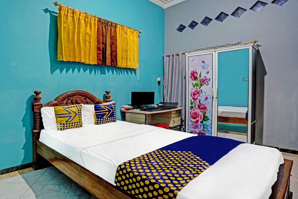 A bedroom with a bed, a desk, a computer, and a wardrobe.