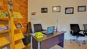 A reception area with a wooden desk, two black office chairs, a laptop, and a calendar on the wall. - Hotel O Desa Wisata Alam Gosari (wagos) (Gresik)