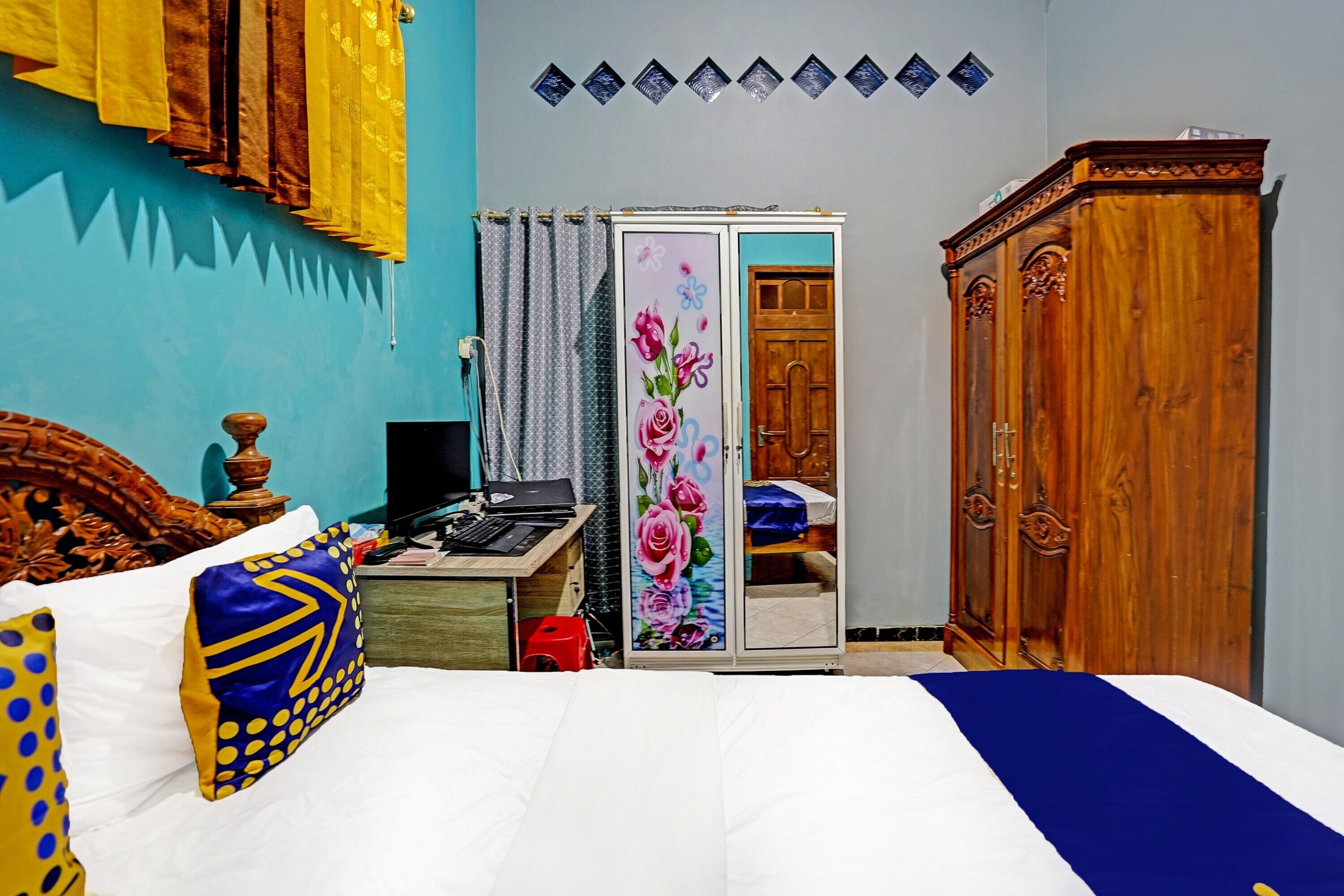 A bedroom with a bed, a desk, a wardrobe, and a door with a floral design.