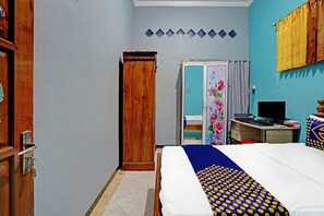 Ein Schlafzimmer mit einem Bett, einem Schrank, einem Schreibtisch mit Computer und einem Fenster mit Vorhängen.