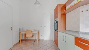 A kitchen with a dining table and chairs, a white door, and a countertop with cabinets. - ITS HOME VIA MODICA (Milano)