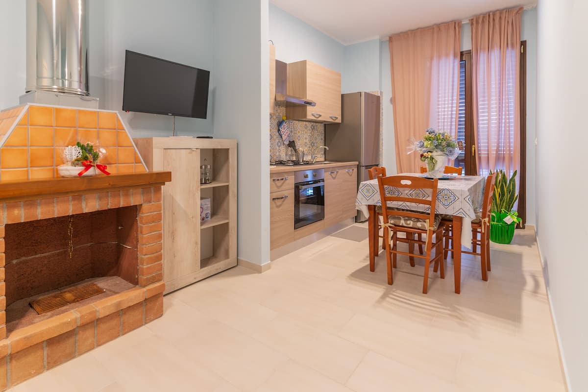 A modern kitchen with a built-in oven, a dining table with chairs, and a TV mounted on the wall.