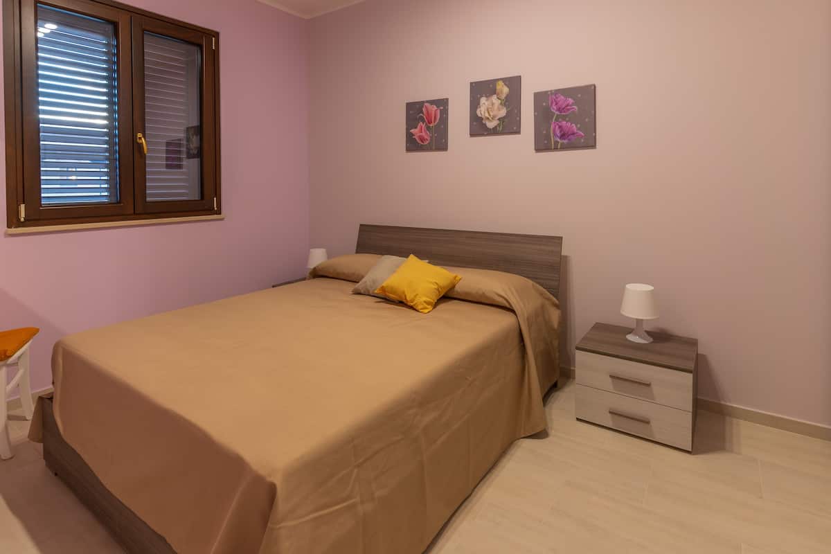 A bedroom with a bed, bedside table, and wall-mounted artwork.