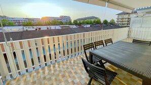 Un balcon avec un sol à carreaux, une table et des chaises.