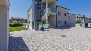 Ein modernes, zweistöckiges Gebäude mit einer zentralen Treppe, einem überdachten Außenbereich und einem courtyard‎ mit Steinpflaster.