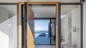 A modern building with a glass door leading to a balcony with a view of the sea. - Stunning sea views, heated pool, fire pit, child pool: by etouri (Chania)