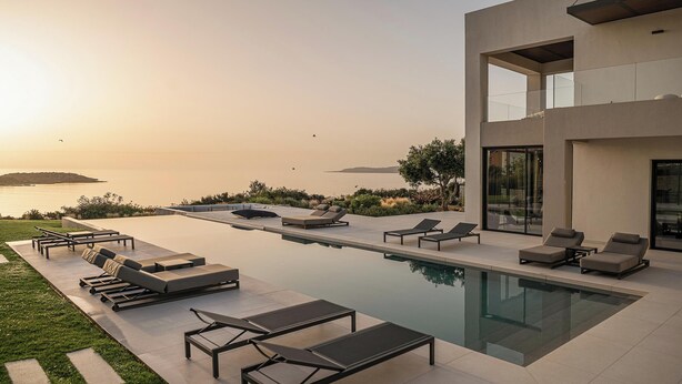 A modern pool area with lounge chairs and a view of the sea. - Stunning sea views, heated pool, fire pit, child pool: by etouri (Chania)