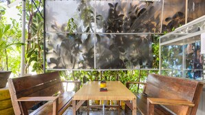 A wooden table and benches in a covered outdoor area with a large reflective art piece above. - Hotel O Bilqis Homestay NearThe Hot River, Dog Run (Batam)