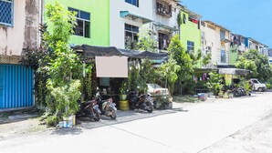 A row of colorful buildings with a row of parked motorcycles in front. - Hotel O Bilqis Homestay NearThe Hot River, Dog Run (Batam)