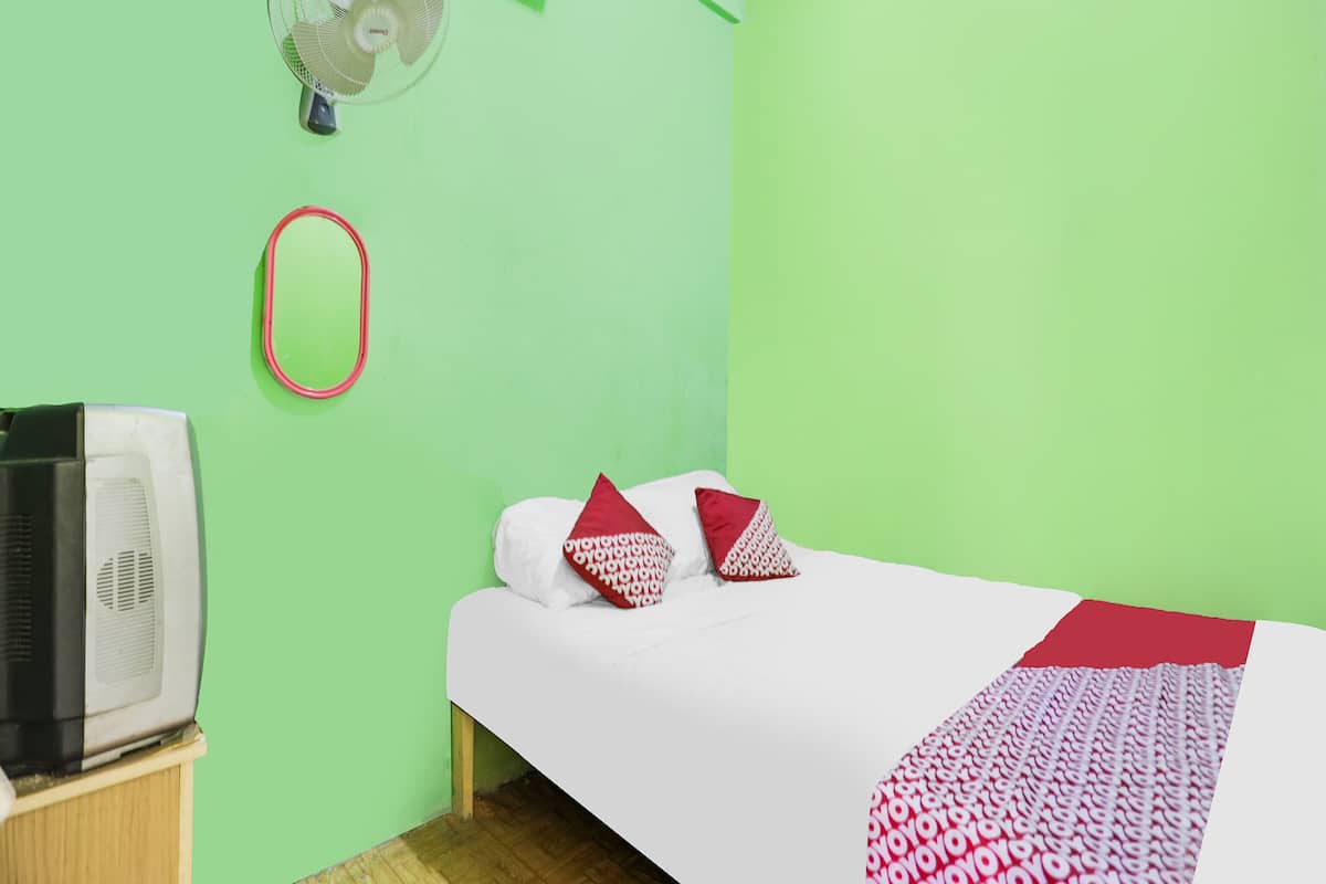 A room with a bed, a fan, and a television on a wooden stand.