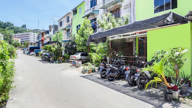 A narrow street lined with colorful buildings, parked motorcycles, and potted plants. - Hotel O Bilqis Homestay NearThe Hot River, Dog Run (Batam)