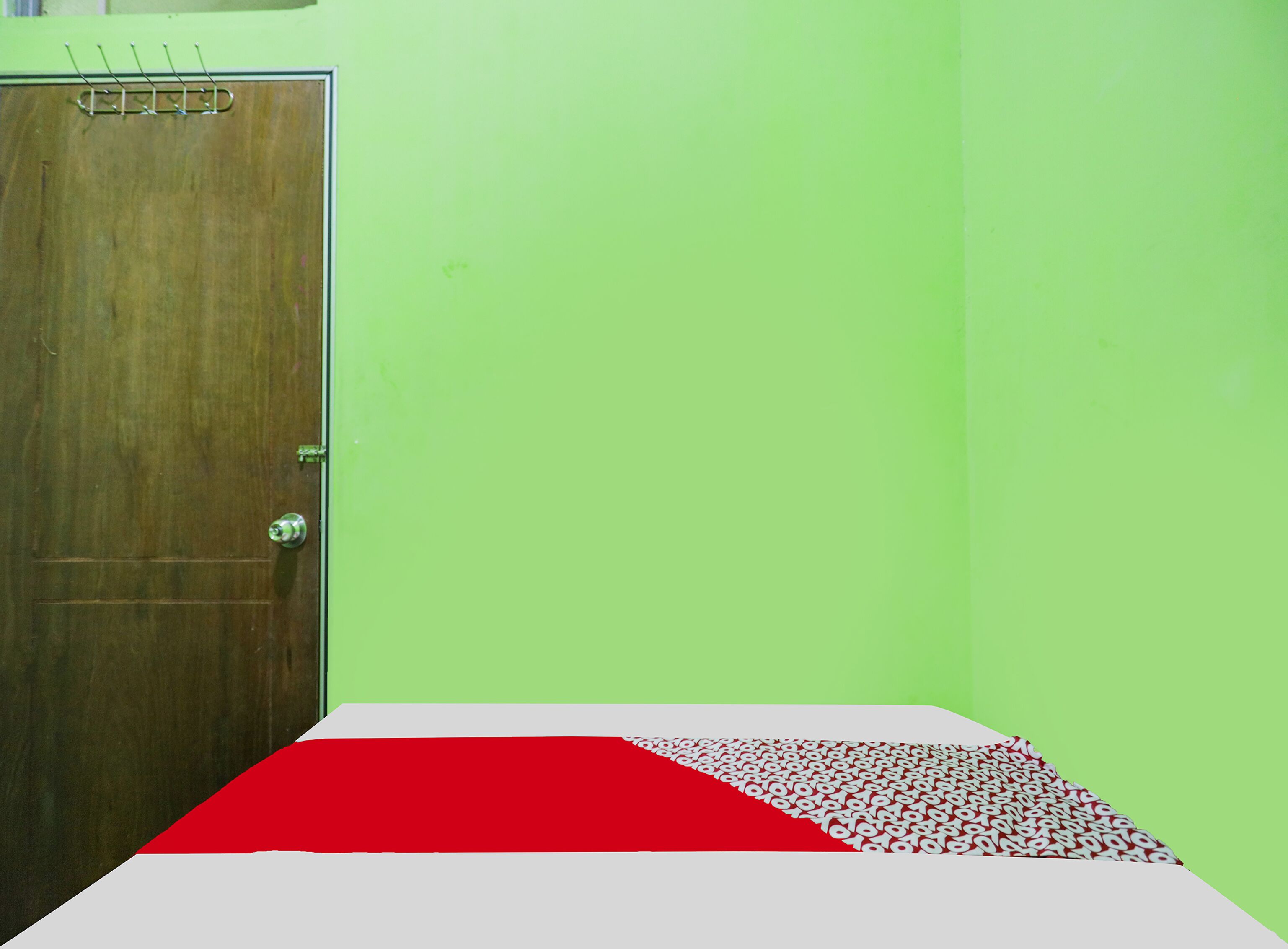 Una habitación con puerta de madera, pared verde y cama con colcha a rayas rojas y blancas.