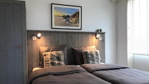 Ein Schlafzimmer mit einem hölzernen Kopfende, zwei Betten und einem gerahmten Bild an der Wand.