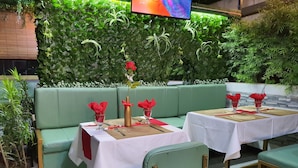 Un restaurant amb seients amb coixins verds i tovallons blancs.