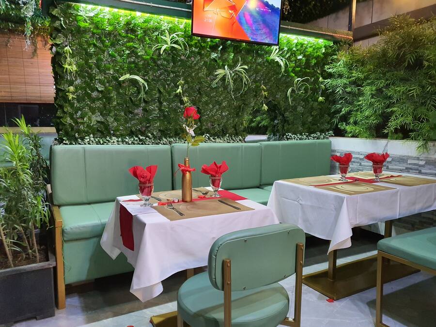 A restaurant with green cushioned seating and white tablecloths.