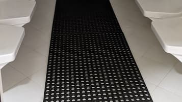 Bathroom features a central mat, tiled walls, and two curved seating areas.