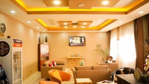 Un vestíbul d'hotel amb sofàs, una televisió, un frigorífic i una màquina expenedora.