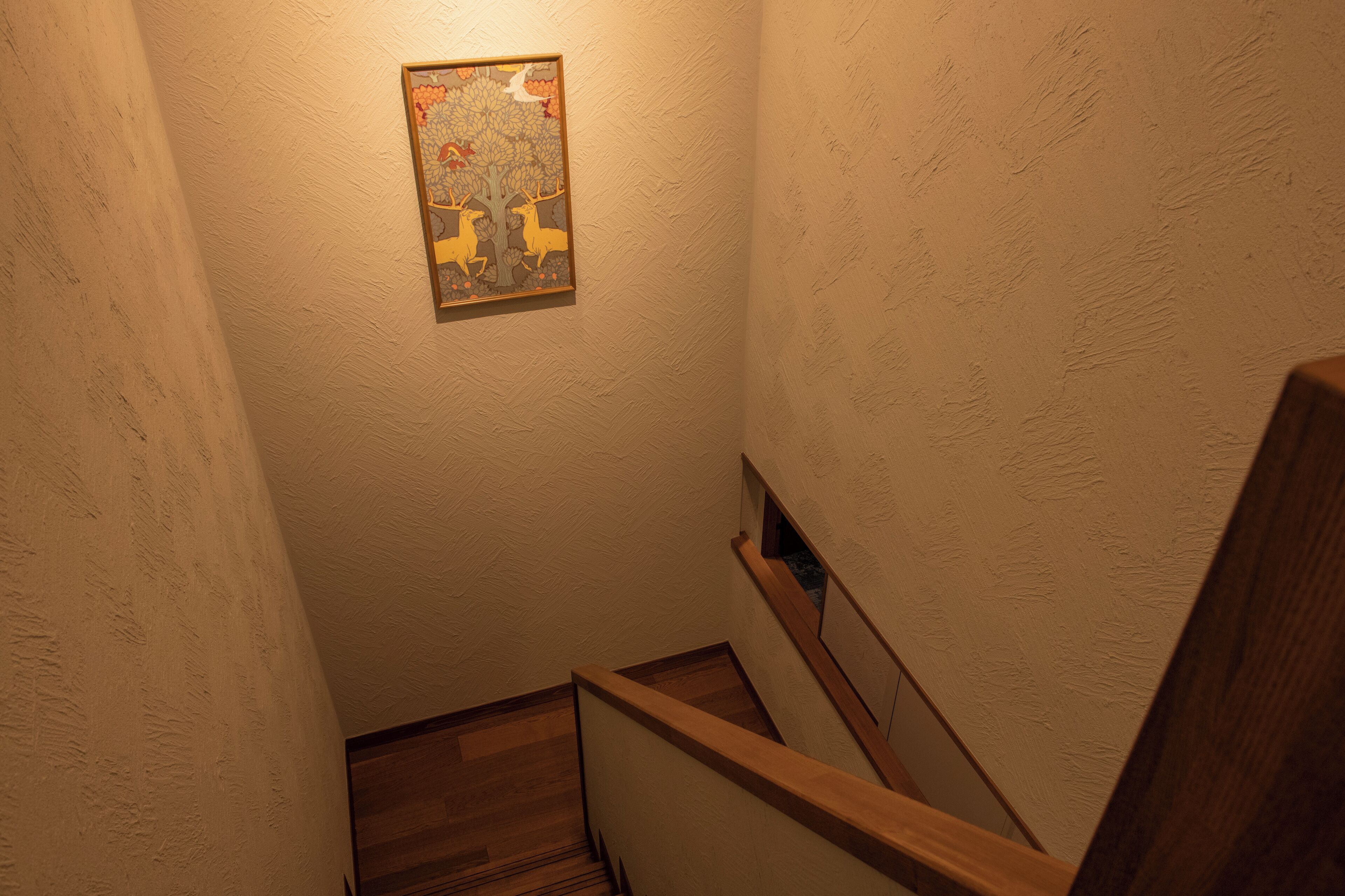 A narrow stairway with wooden handrails and a textured wall.