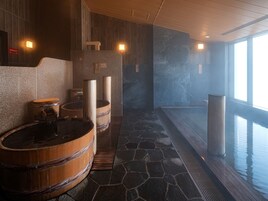 A spa area with stone flooring, wooden tubs, and a large window providing natural light.
