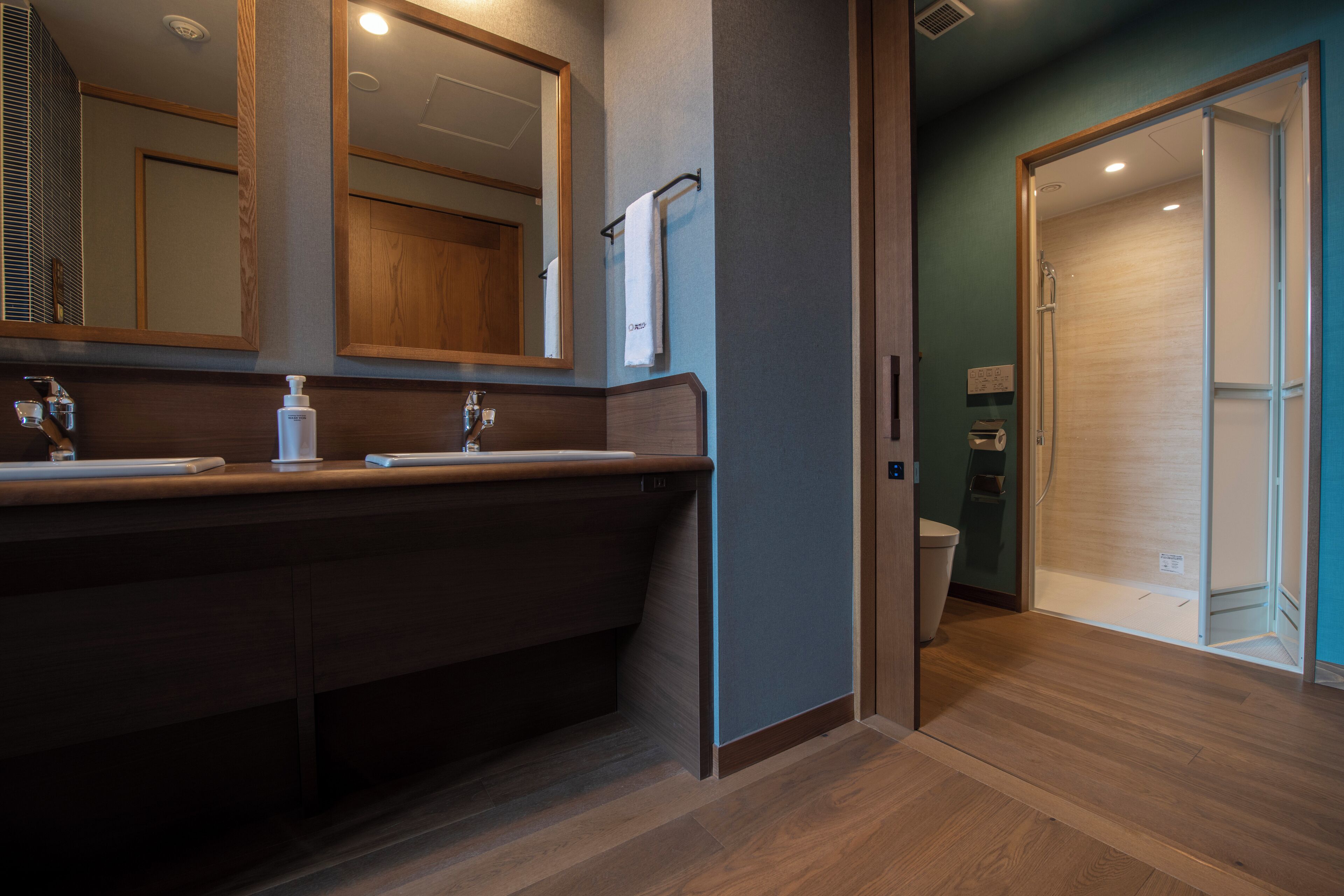 A modern bathroom with a wooden vanity, a large mirror, and a glass shower enclosure.