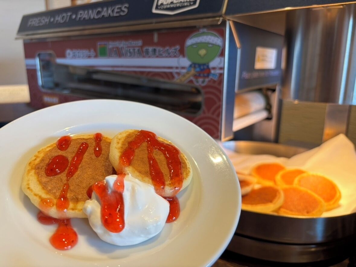 Una colazione con pancake e waffle, una scatola di pancake caldi appena sfornati e un vassoio di spicchi d'arancia.