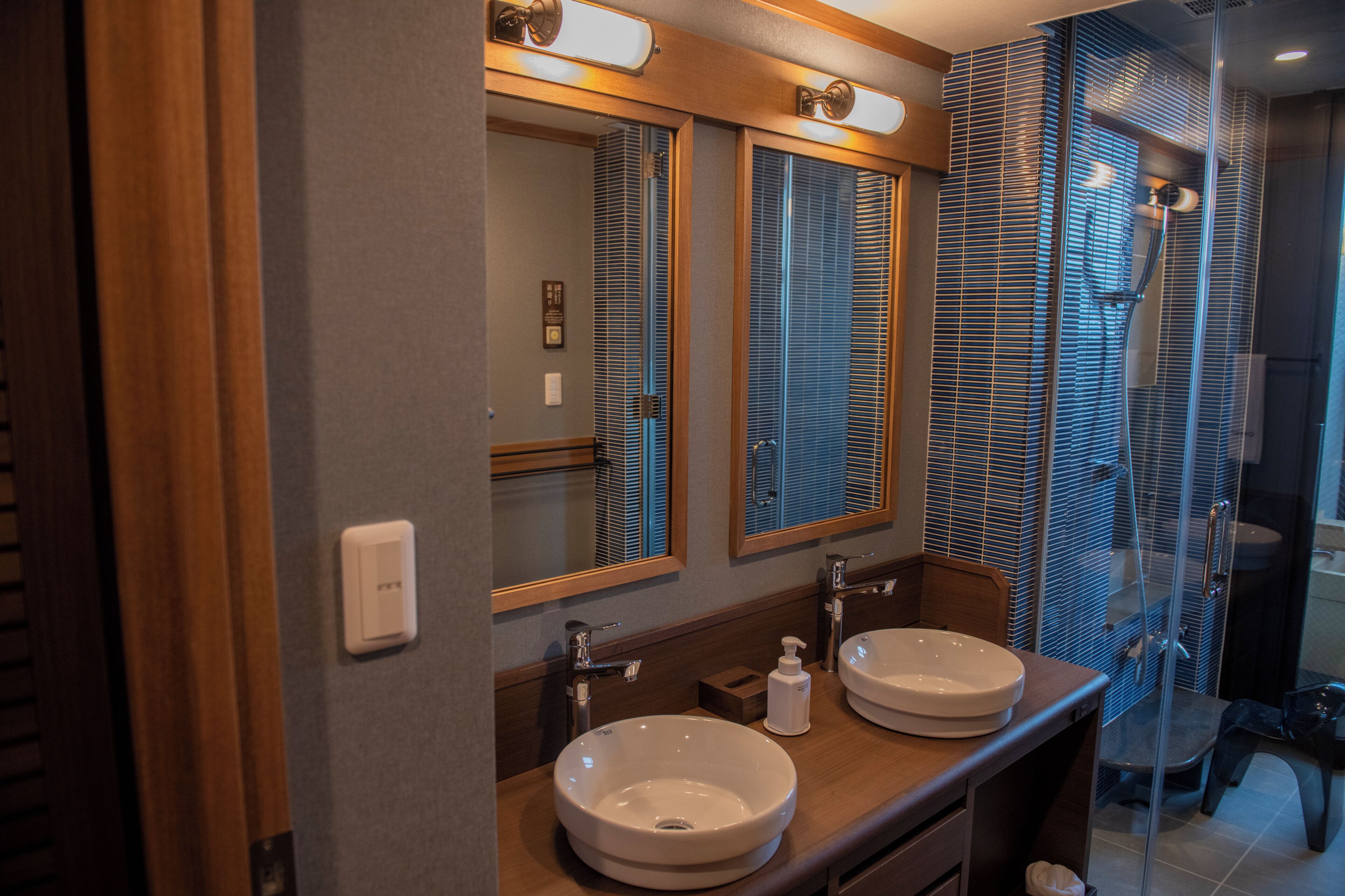 A bathroom with two sinks, a mirror, and a shower area.