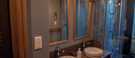 A bathroom with two sinks, a mirror, and a shower area.