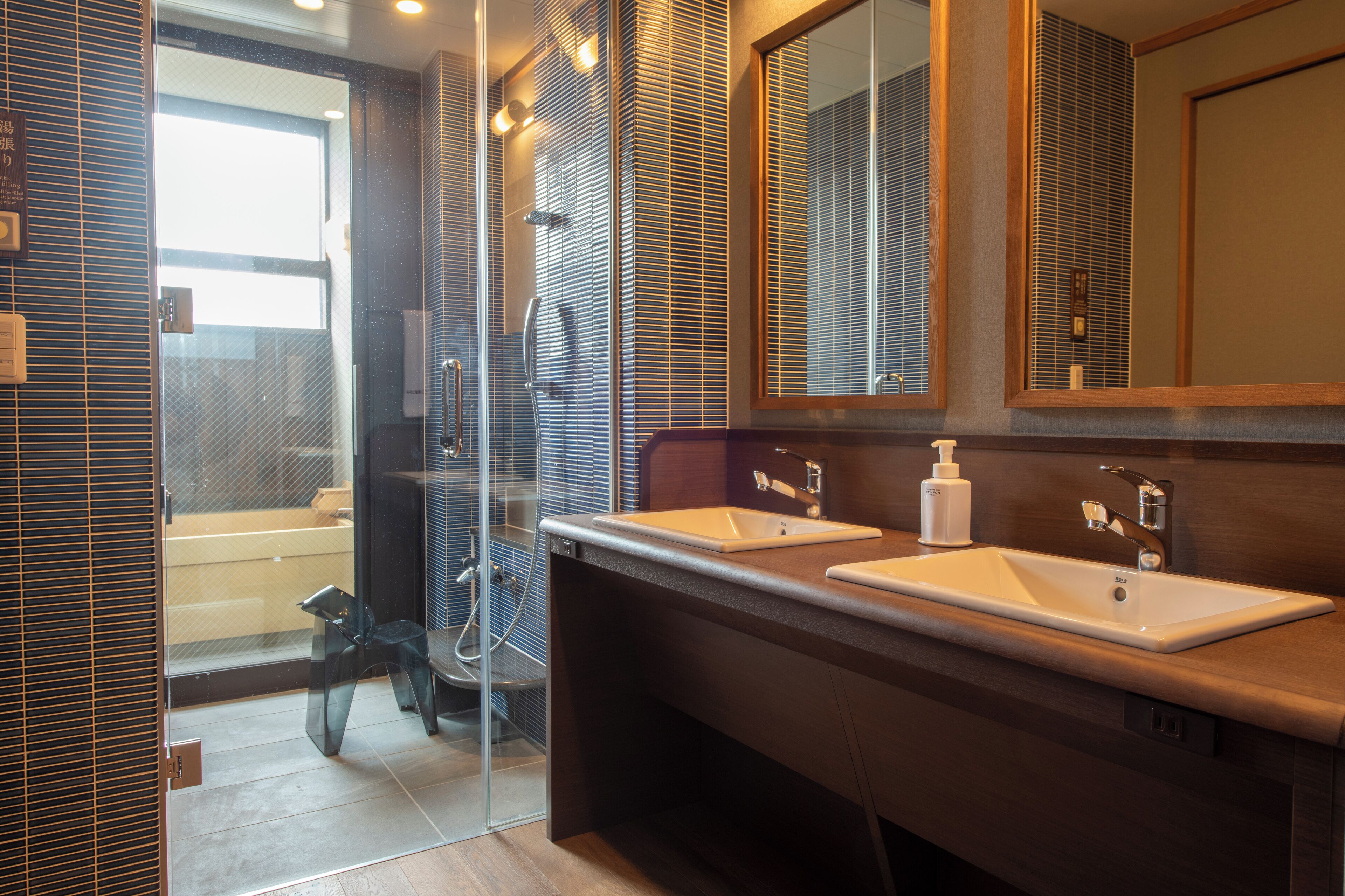 Un baño moderno con dos lavamanos, cabina de ducha con vidrio y un espejo grande.