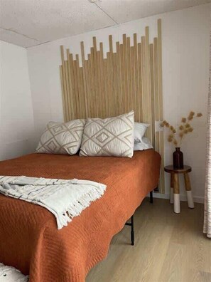 A bedroom with a bed, pillows, a bedside table, and a wall-mounted light fixture.